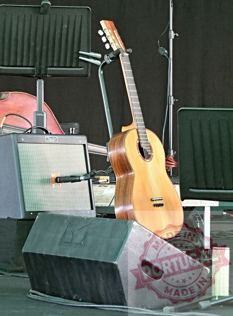 Classical guitar resting on monitor speaker on stage | Classical guitar resting on a monitor speaker, ready for a performance, on a stage - Realized with Pictrs.com