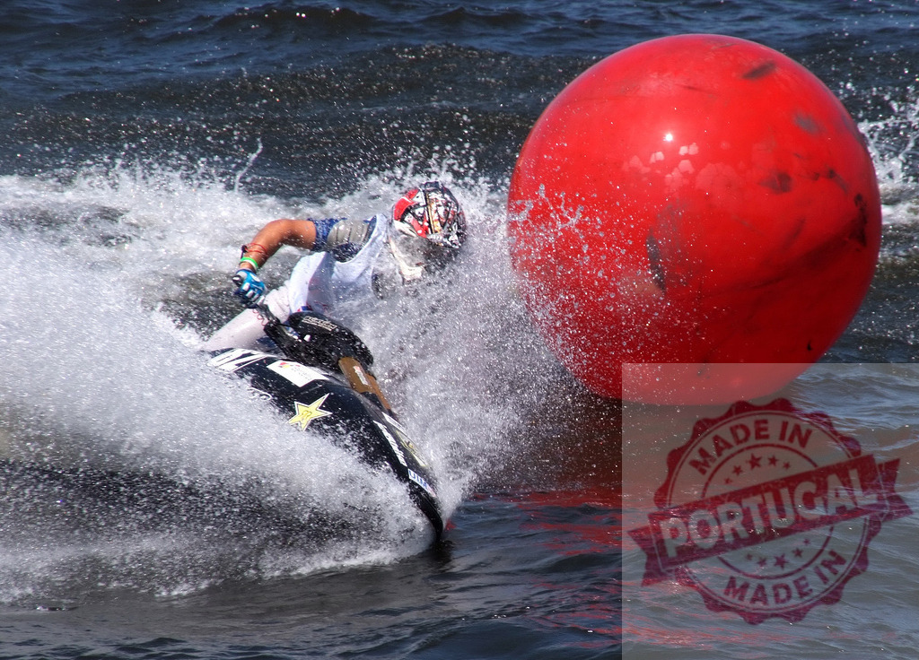 Jet ski pilot splashing water near red buoy during competition | Pilot riding jet ski and splashing water near red buoy during competition - Realisiert mit Pictrs.com