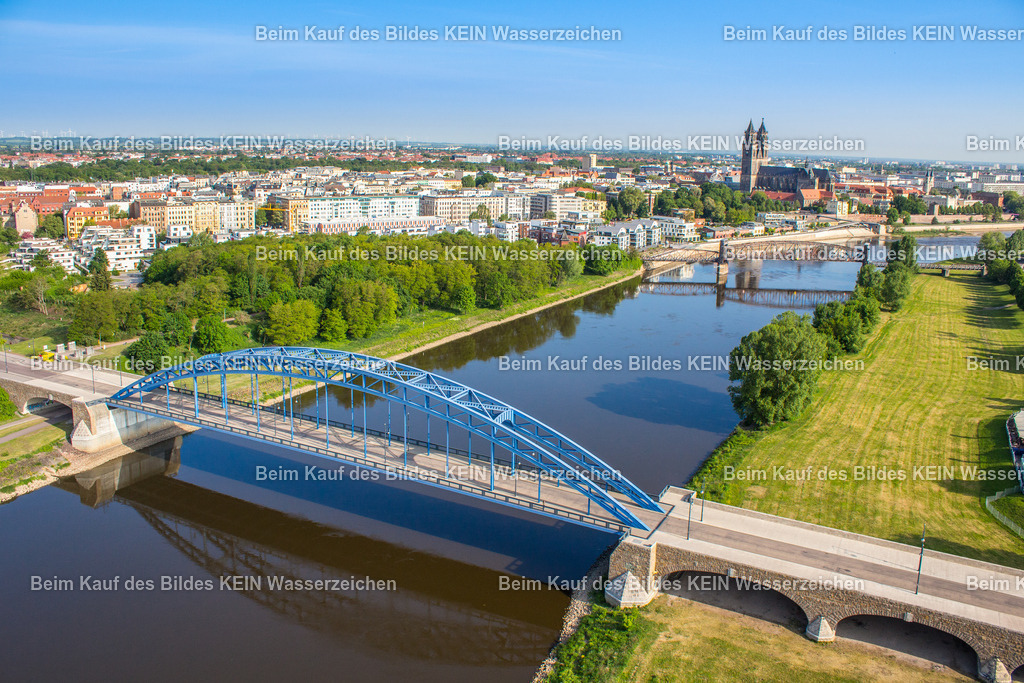 Sternbrücke | Das Luftbild zeigt die Sternbrücke in Magdeburg aus einer Drohnenperspektive. Die markante Stahlbogenbrücke überspannt die spiegelglatte Elbe und spiegelt sich nahezu vollständig auf der ruhigen Wasseroberfläche. Die außergewöhnlichen Lichtverhältnisse und die klare Linienführung der Konstruktion unterstreichen die elegante Ingenieurarchitektur des Bauwerks.Die heutige Sternbrücke wurde zwischen 2002 und 2005 als moderne Stabbogenbrücke neu errichtet. Das Bauwerk besitzt eine Gesamtlänge von 242,2 Metern und eine Hauptspannweite von 137 Metern. Für die Konstruktion wurden rund 900 Tonnen Stahl verbaut. Die Brücke verbindet die Magdeburger Altstadt mit dem Stadtpark Rotehorn und dient als wichtige Verkehrsverbindung für Kraftfahrzeuge, Radfahrer und Fußgänger.Die Drohnenaufnahme macht die symmetrische Stahlkonstruktion und ihre Spiegelung auf der ruhigen Elbe besonders eindrucksvoll sichtbar. Das Zusammenspiel aus moderner Brückenbaukunst, der nahezu spiegelglatten Wasseroberfläche und der außergewöhnlichen Perspektive dokumentiert eines der markantesten Ingenieurbauwerke Magdeburgs in einer technisch wie gestalterisch beeindruckenden Ansicht. - Realisiert mit Pictrs.com