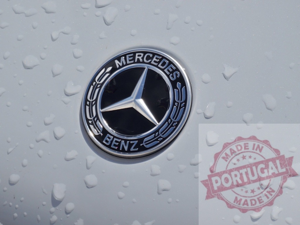 Mercedes-Benz car logo emblem with raindrops on hood | Mercedes-Benz emblem displaying brand identity and luxury on a wet white car surface - Realized with Pictrs.com