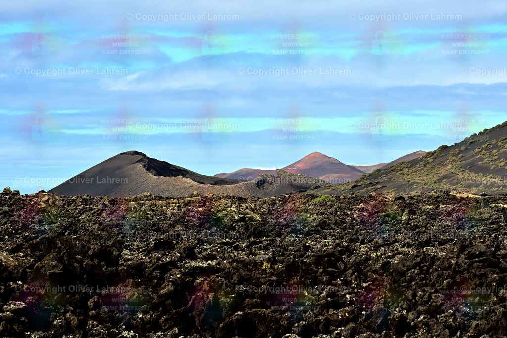 El Cuervo mit Timanfaya | Der markante Krater des " El Cuervo" im Naturpark " Los Volcanes" im Morgenlicht und im Hintergrund sieht man die Vulkane des Timanfaya Nationalpark.