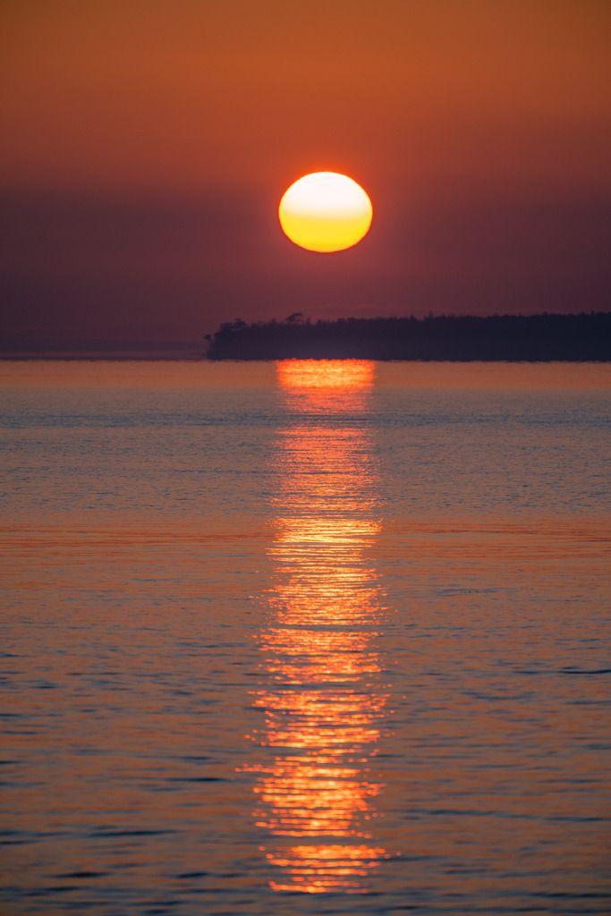 Sonnenuntergang über der Ostsee | Die tief stehende Sonne taucht die Ostsee in warme Orange- und Rottöne. Ihre Spiegelung zieht sich als leuchtende Spur über die ruhige Wasseroberfläche bis zum Horizont. - Realisiert mit Pictrs.com