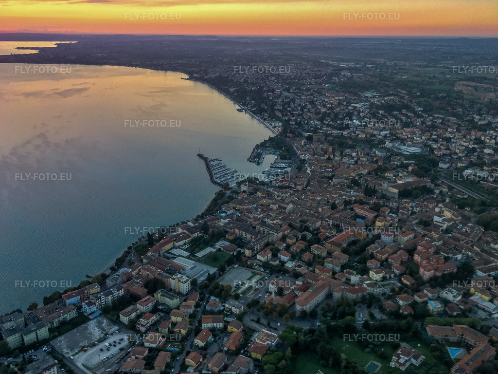 Vue aérienne: Lever de soleil sur le lac de Garde à Desenzano del Garda dans le département Brescia, Italie. Photo: IMG-134977.jpg prise le 23/09/2022 par Werner Riehm/FLY-FOTO.eu – Résolution de l'original: 3926 x 2945 px