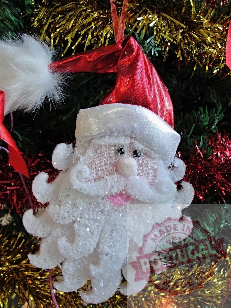Santa claus ornament hanging on christmas tree with sparkling tinsel | Santa claus ornament hanging on artificial christmas tree with red and gold sparkling tinsel - Realized with Pictrs.com