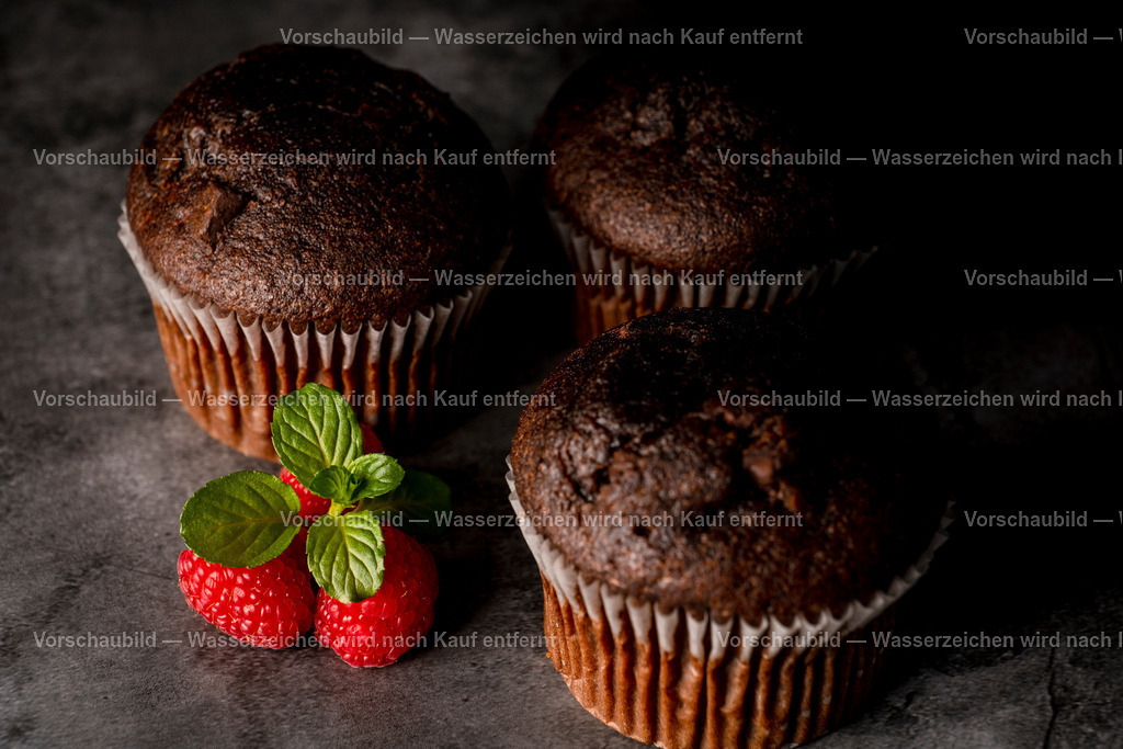 Schokomuffins, dekoriert mit Himbeeren und Minzblatt. | Schokomuffins, dekoriert mit Himbeeren und Minzblatt. Low Key Aufnahme - Realisiert mit Pictrs.com