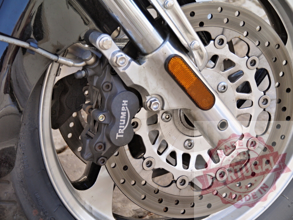 Triumph motorcycle front wheel with disc brake system | Triumph motorcycle front wheel featuring a modern disc brake caliper, rotor, and suspension fork tube - Realisiert mit Pictrs.com