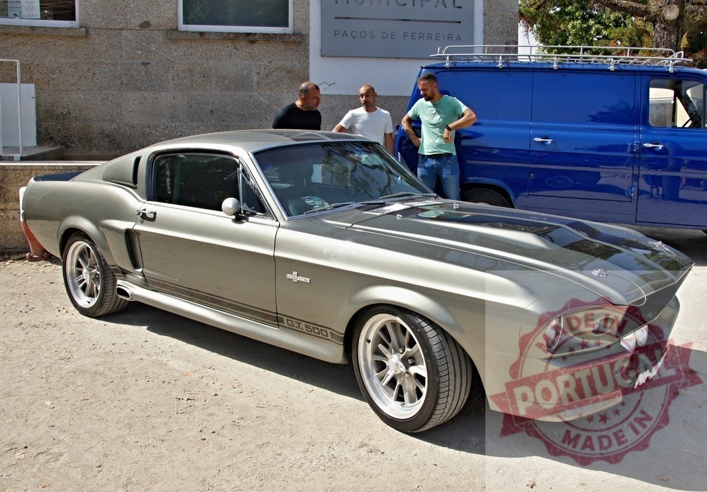Ford Mustang Shelby GT500 Eleanor replica parked at car show in Paços de Ferreira | Ford Mustang Shelby GT500 Eleanor replica parked outdoors with two men chatting nearby, representing speed and classic automotive power - Realisiert mit Pictrs.com