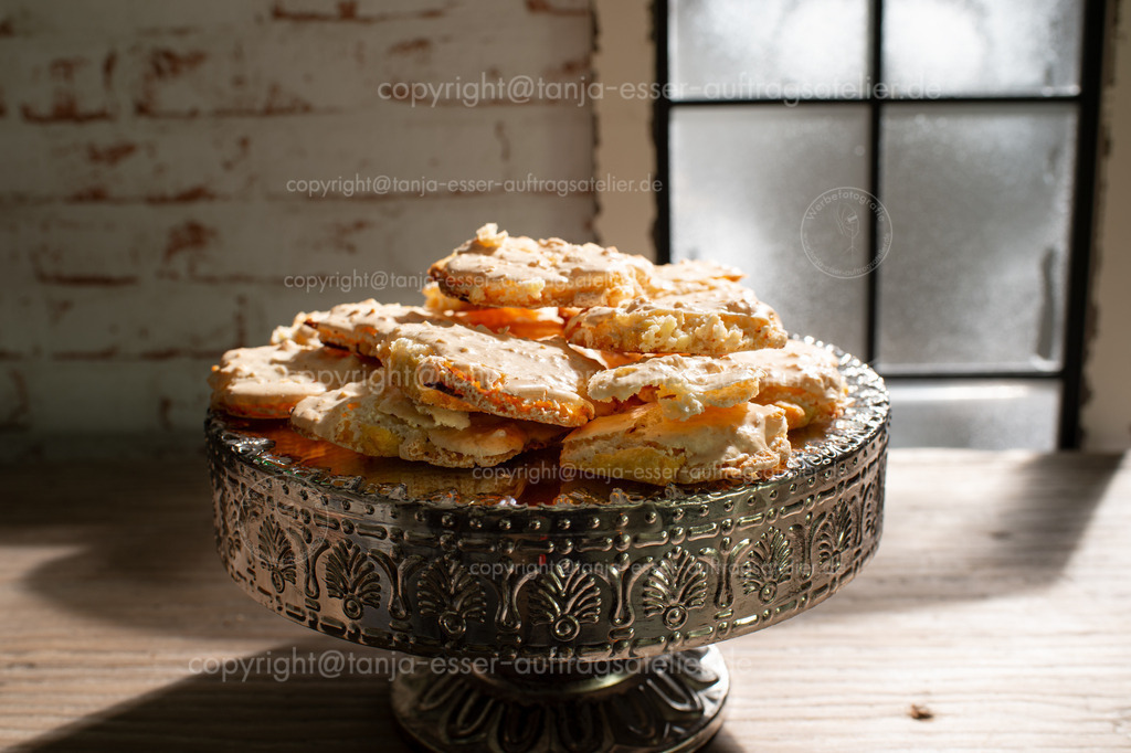 Vor einem vereisten Fenster liegen Mandelrhomben, ein Adventsgebäck aus Mürbeteig mit einer Haube aus Eischnee. Die rhombusförmigen Plätzchen sind goldbraun gebacken und sehen köstlich aus für einen gemütlichen Nachmittag im Winter. | Vor einem vereisten Fenster liegen Mandelrhomben, ein Adventsgebäck aus Mürbeteig mit einer Haube aus Eischnee. Die rhombusförmigen Plätzchen sind goldbraun gebacken und sehen köstlich aus für einen gemütlichen Nachmittag im Winter.