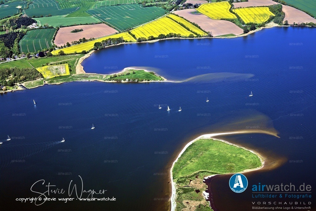 Luftbild Ostseefjord Schlei, Boren-Lindaunis Schleibrücke, Campingplatz Lindaunis, Sportboothafen Lindaunis | Die Schlei ist ein tief ins Binnenland von Schleswig-Holstein reichender Meeresarm der Ostsee und gilt als ein besonders geschütztes Binnenrevier für Segler. Mit einer Länge von etwa 42 Kilometern erstreckt sie sich von der Schleimündung bei Maasholm bis zur Stadt Schleswig und hat eine Wasserfläche von 54,6 km².  Sie trennt die Landesteile Angeln und Schwansen und ist durch ihre geringe Tiefe von durchschnittlich drei Metern sowie ihre Brackwasser-Mischung charakterisiert. Die Schlei wird aufgrund ihrer Entstehungsgeschichte und geografischen Gegebenheiten als Binnenrevier angesehen, obwohl ihre Einordnung als Förde umstritten ist. Die Strömungsgeschwindigkeit ist in der Regel sehr gering, was die Schlei zu einem idealen Revier für Wassersportarten wie Segeln, Windsurfen und Kitesurfen macht.