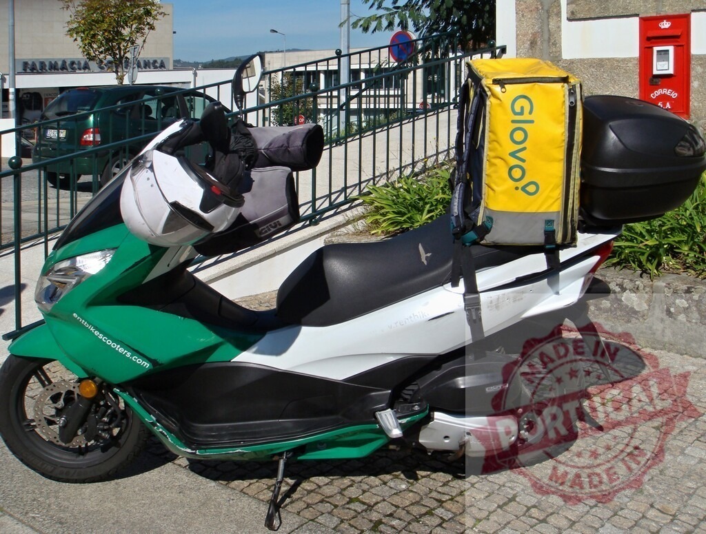Glovo delivery scooter with backpack parked on street | Glovo delivery scooter parked in an urban environment, showing the delivery backpack and helmet - Realized with Pictrs.com