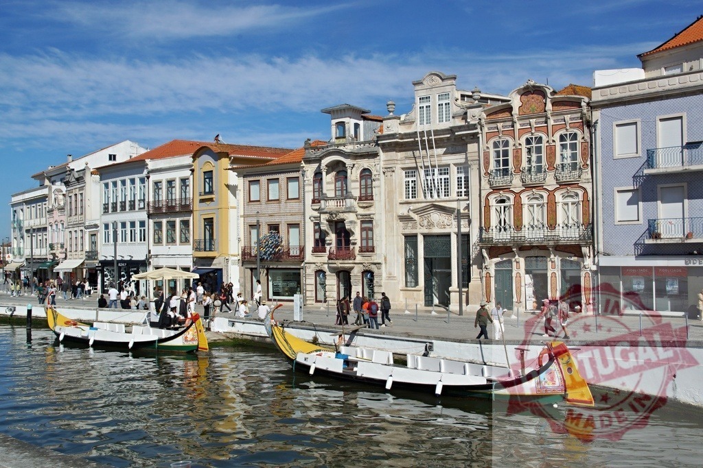 Moliceiro boats on canal in Aveiro, Portugal cityscape. Aveiro - Portugal | Traditional moliceiro boats navigating a canal in the historic city center of Aveiro, Portugal - Realized with Pictrs.com