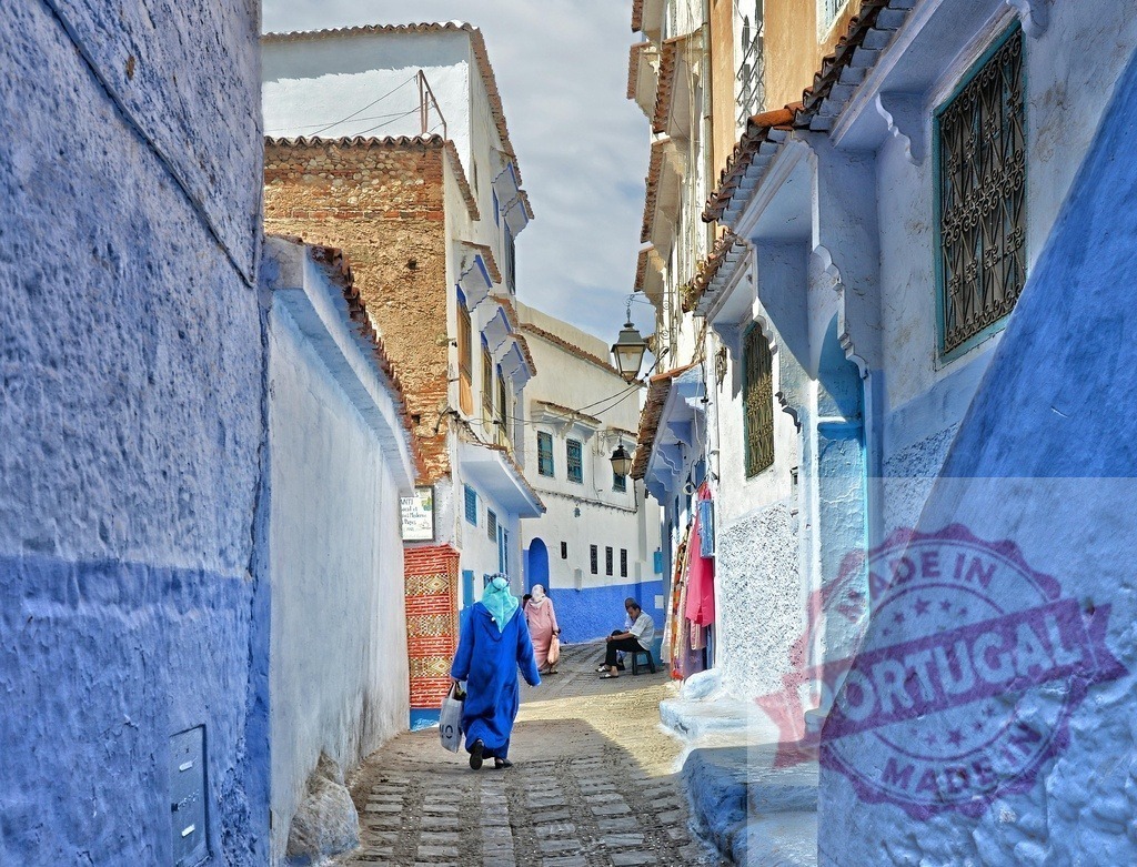 Chefchaouen blue city alley with people walking | People walking along a narrow blue street in the famous mountain town of Chefchaouen, Morocco - Realized with Pictrs.com