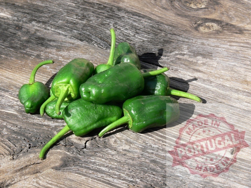 Padrón peppers pile on rustic wood background | Green Padrón peppers resting on a vintage wooden surface in sunlight - Realized with Pictrs.com