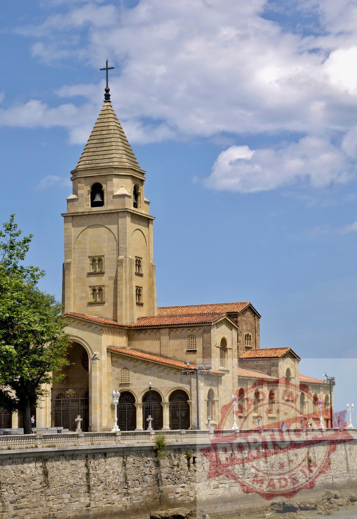 San Pedro church building on Gijón coastline | San Pedro church standing on a stone wall along the coast under a blue sky - Realisiert mit Pictrs.com