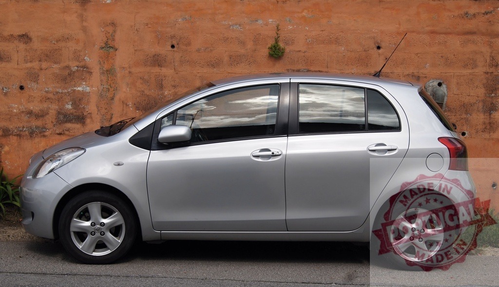 Toyota Yaris silver hatchback car parked outdoors | Toyota Yaris subcompact car parked beside an old orange wall on a sunny day - Realisiert mit Pictrs.com