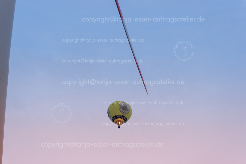 139 Ballons und Windrad | Warsteiner Internationale Montgolfiade ist die Veranstaltung mit Heißluftballons. Warsteiner Ballon in der Nähe eines Windrads.