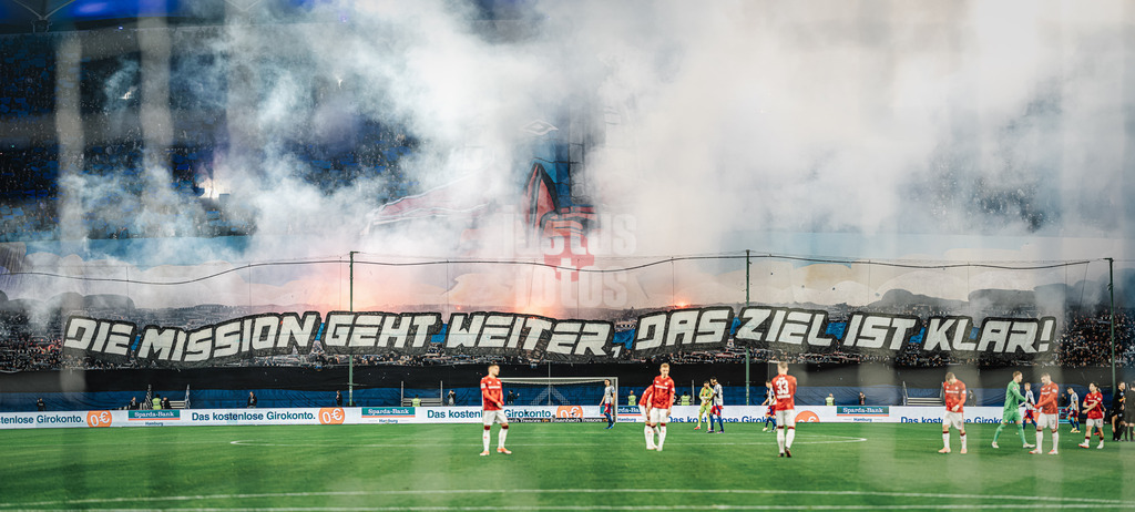 Fußball | Männer | Saison 2024/2025 | 2. Fußball-Bundesliga | 23. Spieltag | Hamburger SV vs. 1. FC Kaiserslautern | 21.02.2025 | Choreo der HSV Nordtribüne Fans Die Mission Geht Weiter Das Ziel Ist Klar mit Pyrotechnik zusammengefügtes Panorama