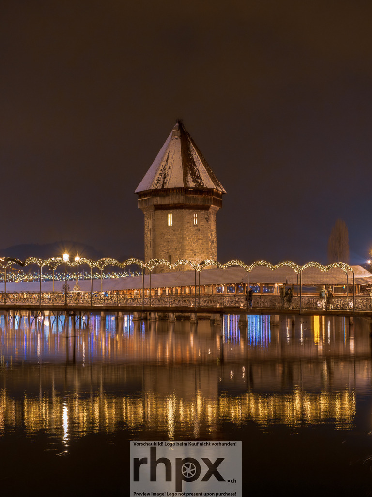 Kapellbrücke im Weihnachtsglanz | Lichter. Wasser. Magie.Dieses Bild fängt die einzigartige Atmosphäre der Kapellbrücke zur Weihnachtszeit ein. Die Lichter spiegeln sich in der Reuss und tauchen das Wahrzeichen in einen goldenen Glanz. Hol dir diese festliche Ruhe als Wandbild in dein Wohnzimmer. - Realisiert mit Pictrs.com