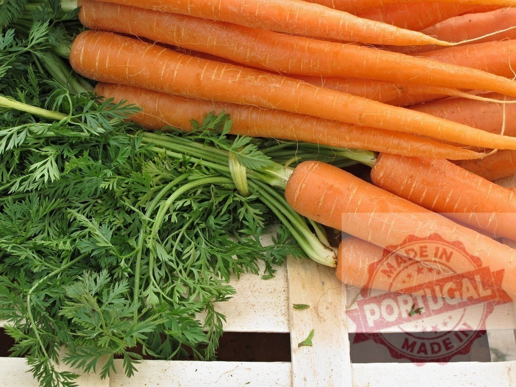 Fresh organic carrots with green tops in market crate | Fresh carrots with green leaves are resting in a wooden crate, ready for healthy eating - Realized with Pictrs.com