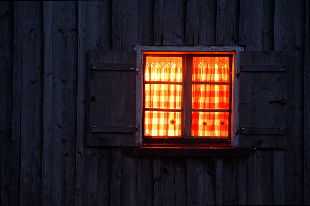 Holzhaus mit Fensterbeleuchtung | Schoenenbach, Austria - July 23, 2012: Vorsäßsiedlung Schönenbach;  Holzhaus mit beleuchtetem Fenster am Abend. - Realisiert mit Pictrs.com