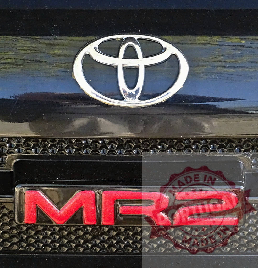 Toyota MR2 sports car logo and emblem | Toyota MR2 brand badge on car grille with chrome logo - Realized with Pictrs.com