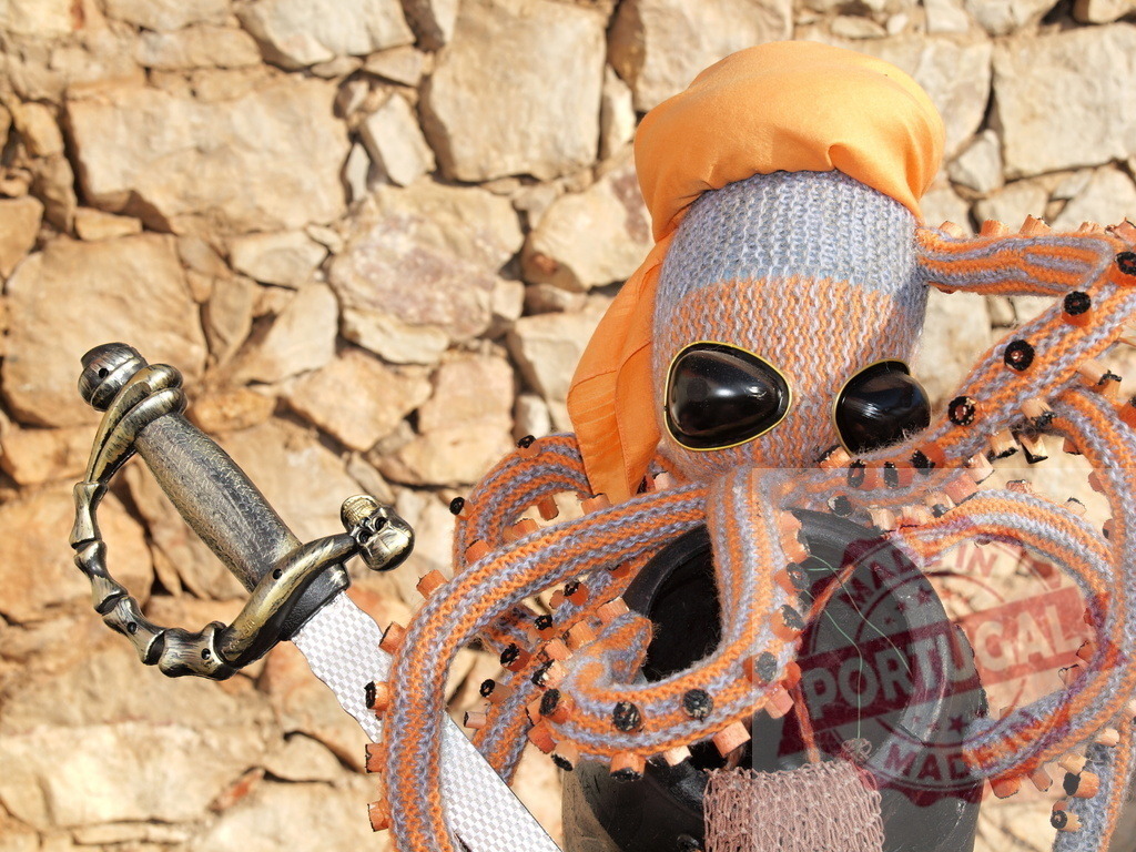 Knitted pirate octopus toy holding a sword | Handmade knitted octopus wearing a pirate costume with a sword against a stone wall - Realized with Pictrs.com