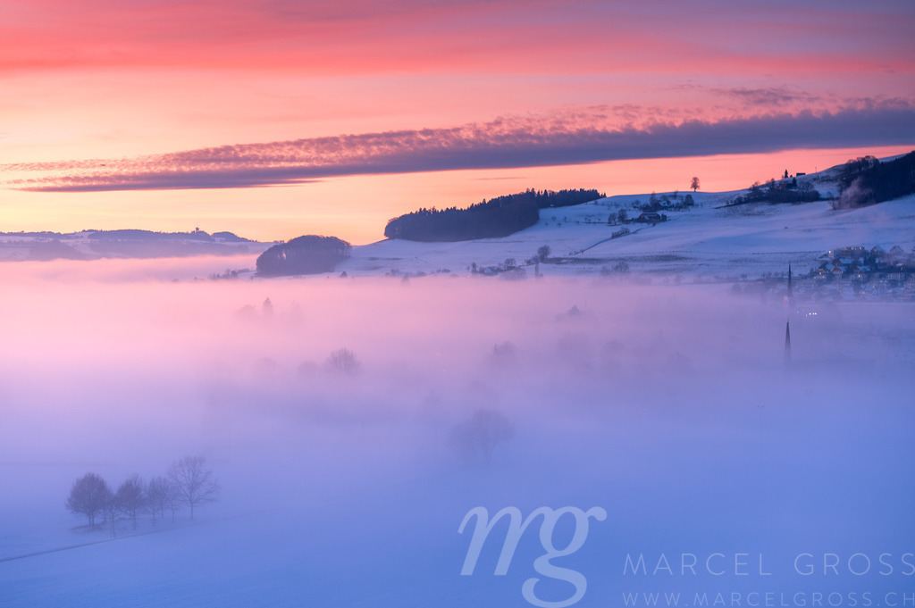 Kitschiger Wintersonnenuntergang über Konolfingen mit Blick aufs Nebelmeer | Die ideale Geschenkidee für Naturliebhaber. Naturbilder von Marcel Gross Photography für ihr Zuhause in den verschiedensten Formaten und Materialien. - Realisiert mit Pictrs.com