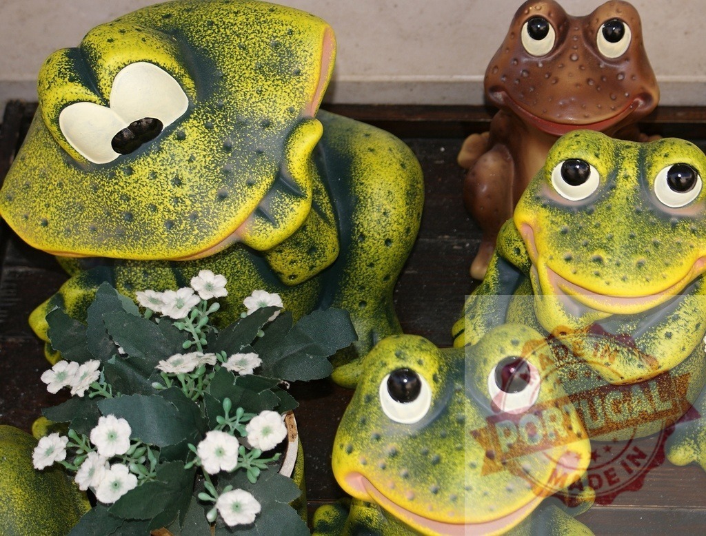 Ceramic frog figurines displaying kitsch garden ornaments | Ceramic frog figurines smiling, green, and brown, arranged as garden ornaments - Realisiert mit Pictrs.com