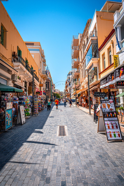 2026-07-20_10-59-52_850 | Belebte Einkaufsstraße mit zahlreichen Geschäften, Passanten und sommerlichem Himmel, Heraklion, Kreta, Griechenland - Realisiert mit Pictrs.com