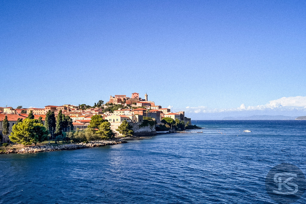 Panorama von Portoferraio: Historische Hafenstadt auf Elba – Exklusives Wandbild | Weitwinkelaufnahme der Hafenstadt Portoferraio auf Elba mit Blick über das blaue Meer auf die historischen Festungsmauern und die terrassenförmige Altstadt unter strahlend blauem Himmel. - Realisiert mit Pictrs.com