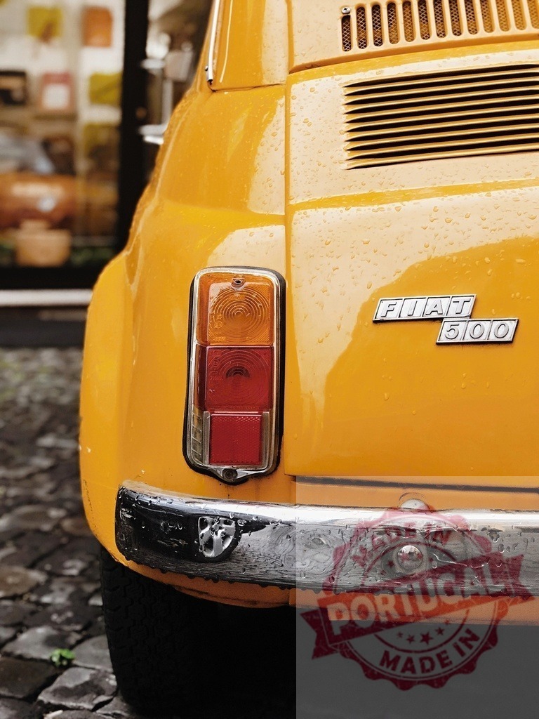 Classic yellow FIAT 500 parked on cobblestone street after the rain | Rear view of vintage yellow FIAT 500 with raindrops, parked on a cobblestone street - Realized with Pictrs.com