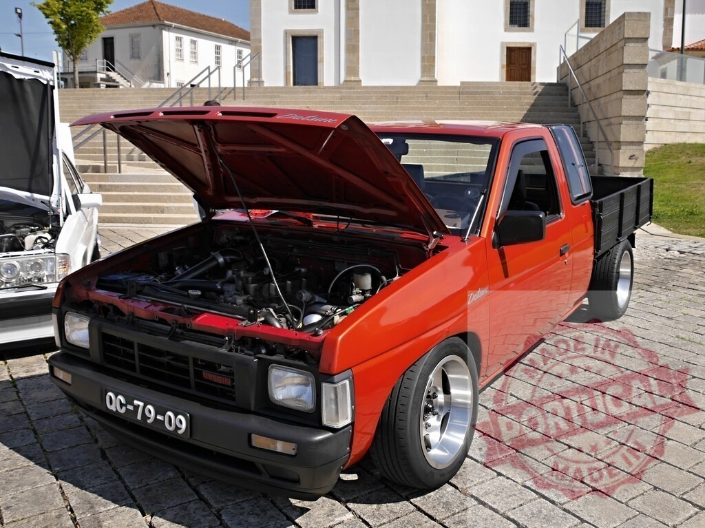 Red Nissan Datsun pickup truck with open hood | Red Nissan Datsun pickup truck with open hood displaying engine at car show - Realized with Pictrs.com