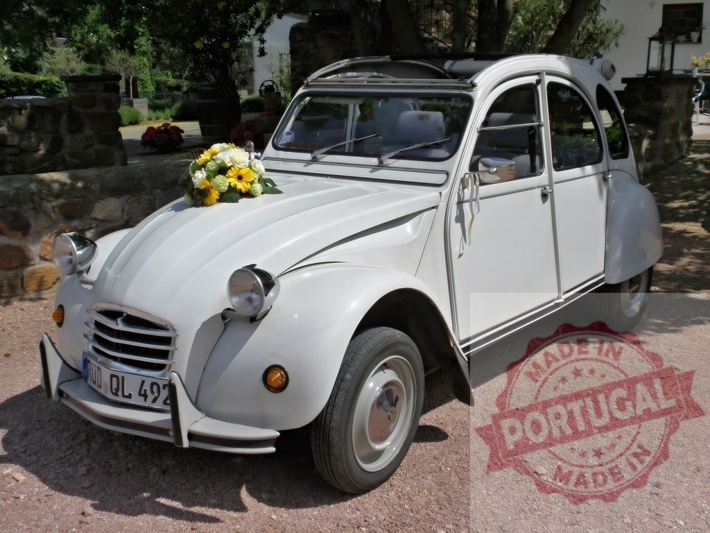 White Citroën 2CV wedding car with flower bouquet | Classic French Citroën 2CV decorated with a wedding flower bouquet on a gravel road - Realisiert mit Pictrs.com