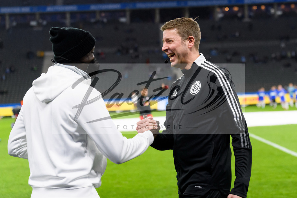BSCRBL20220220_259 | Fussball, Herren: Schiedsrichterassistent Guido Kleve und Teammanager Babacar N'Diaye (RB Leipzig) begruessen sich bei dem Spiel der 1. Bundesliga zwischen Hertha BSC und RB Leipzig im Olypiastadion am 20.02.2022 in Berlin, Deutschland.DFB / DFL REGULATIONS PROHIBIT ANY USE OF PHOTOGRAPHS AS IMAGE SEQUENCES AND/OR QUASI-VIDEO. - Realisiert mit Pictrs.com