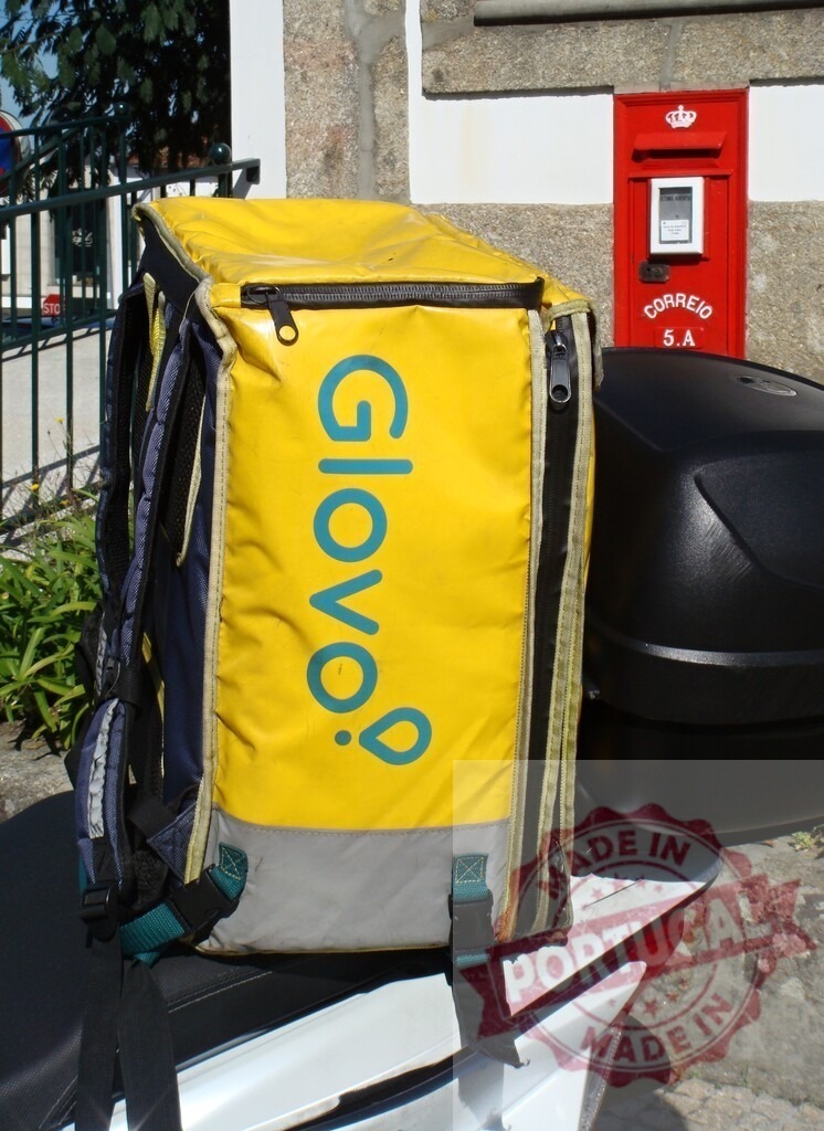 Glovo delivery bag on scooter near Portuguese mailbox | Glovo thermal delivery backpack resting on a scooter seat next to a red postal box - Realized with Pictrs.com