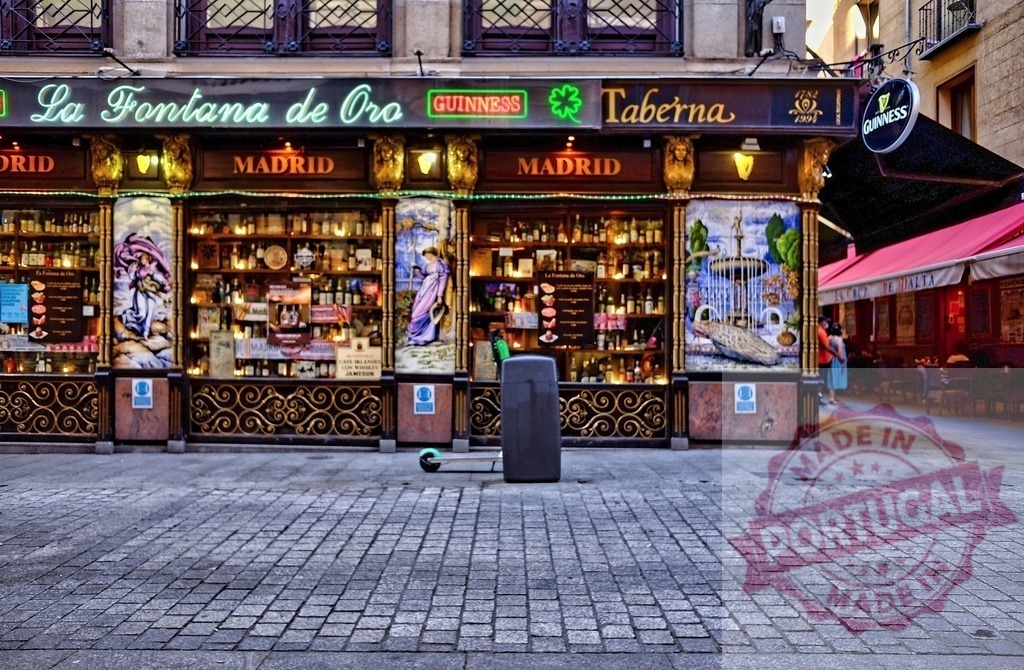 La Fontana de Oro Madrid tavern storefront at night | La Fontana de Oro, a historic tavern with illuminated signage and decorative facade, stands on a cobblestone street - Realisiert mit Pictrs.com