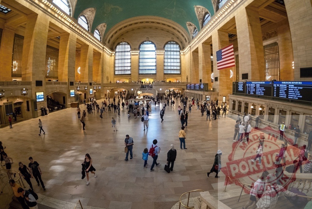 Tourists walking in Grand Central Terminal main concourse in New York City | Tourists and locals walking in Grand Central Terminal main concourse in New York City with American flag - Realized with Pictrs.com