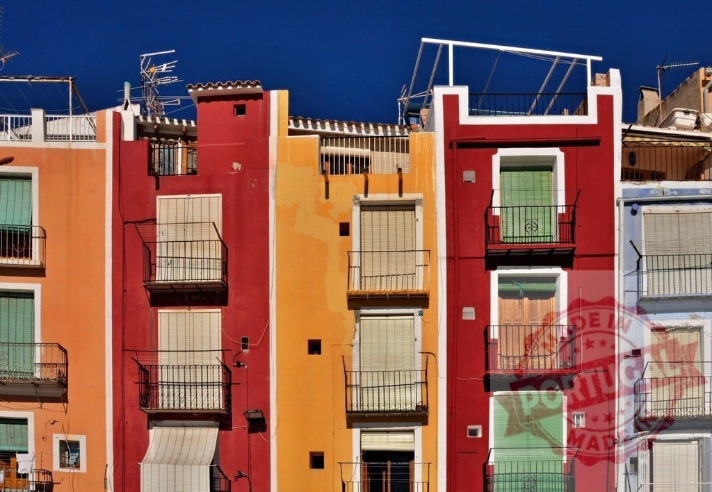 Colorful facades with balconies in Mediterranean city | Row of colorful residential building facades with small balconies and closed shutters under blue sky - Realisiert mit Pictrs.com