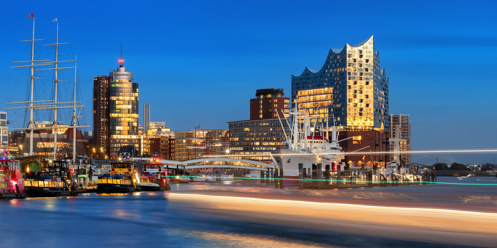 10230203 - Moving Lights | Blaue Stunde an den Landungsbrücken mit Blick auf die Elbphilharmonie und die Lichter einer Hafenfähre.