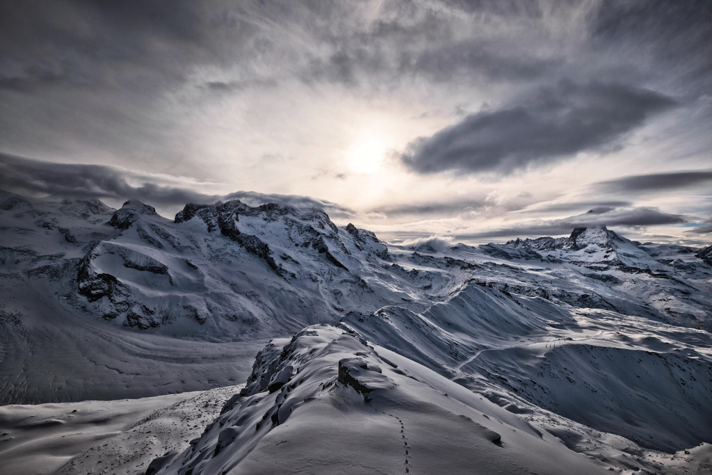 Hohtälligrat | Ridge leading to the Gornergrat with the Gornergrat railway station (3090 m). In the background (in the clouds) the Matterhorn.  I had taken this picture before my last downhill skiing of the day; down to Zermatt in this memorable light.
----
Der Hohtälligrat ist der Verbindungsgrat zwischen dem Gornergrat und dem Hohtälli auf rund 3800 Metern Höhe. Links ist der Gornergletscher zu sehen, im Hintergrund das Matterhorn. Ich machte das Bild vor meiner letzten Abfahrt des Tages in diesem unvergesslichen Licht. Als Zusatzfreude war die Strecke bis Sunnegga weitgehend menschenleer. - Realisiert mit Pictrs.com
