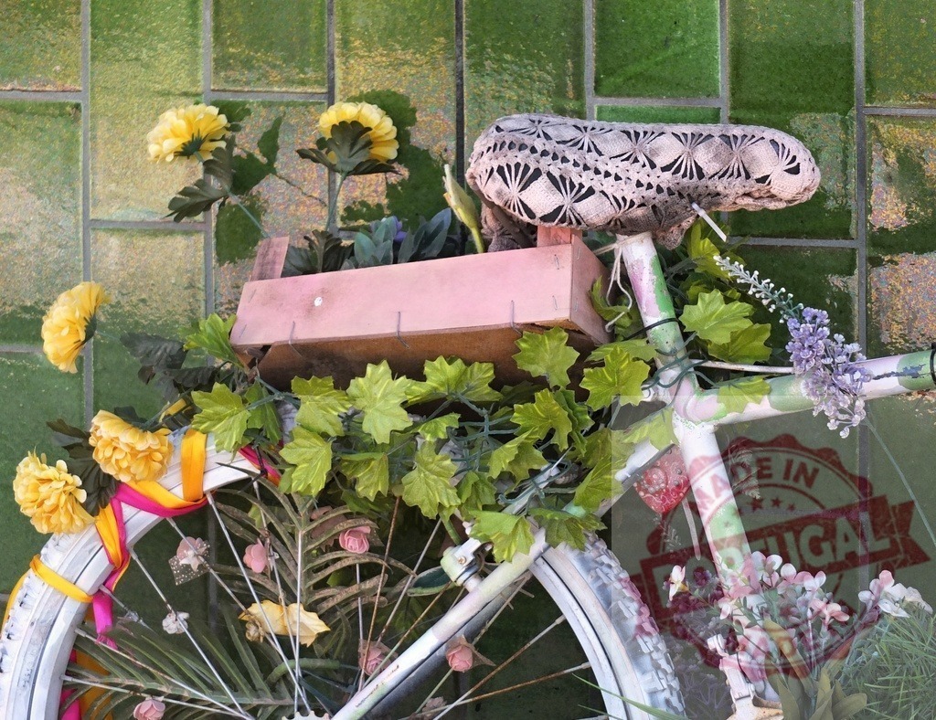 Decorative bicycle creating a rustic floral display | Decorated bicycle with flowers and vines against a green tiled wall - Realisiert mit Pictrs.com
