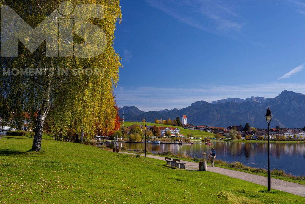 2.Liga-1860-HEIM.jpg | 17.10.2022, Herbst am Hopfensee im Allgäu (Bayern) bei Füssen. Bei sommerlichen Temperaturen geniessen viele Ausflügler die herbstliche Landschaft am See. Hier die Promenade in Hopfen am See. - Realisiert mit Pictrs.com