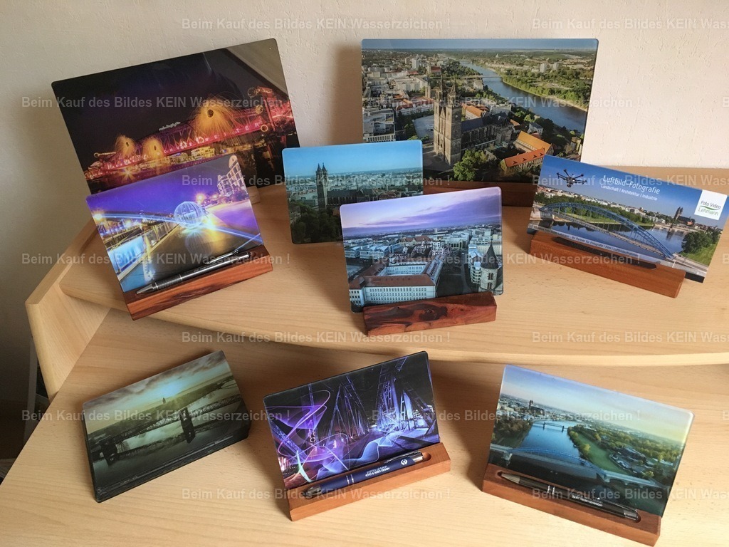 luftbild-magdeburg-tisch-magdeburger-platte-steffen-lehmann _8540 | Acht „Magdeburger Platten®“ mit unterschiedlichen Motiven und in verschiedenen Größen – einige mit Holzaufsteller, andere noch mit einem einfachen Kunststoffaufsteller. So sahen meine ersten Versuche aus, aus meinen Luftbildern von Magdeburg ein kleines regionales Präsent zu entwickeln.Damals habe ich vieles einfach ausprobiert: verschiedene Größen, Motive und auch einmal Lichtkunstfotografie auf Acrylglas. Der Schreibtisch war dabei gewissermaßen mein kleines Versuchslabor.Noch war nicht klar, wohin sich die Idee entwickeln würde. Aber genau aus diesen ersten Versuchen entstand nach und nach die Magdeburger Platte® – ein Luftbild von Magdeburg auf Acrylglas und später sogar eine eingetragene Marke. - Realisiert mit Pictrs.com