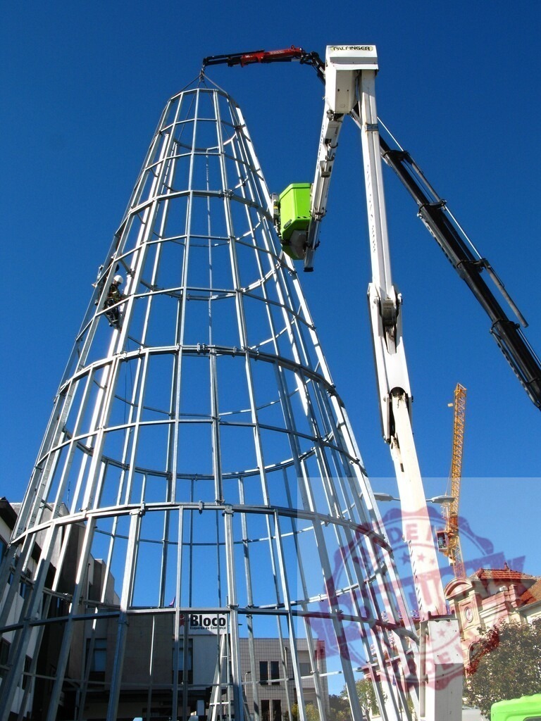 Workers assembling christmas tree metal frame using crane and lift platform | Workers assembling large christmas tree metal frame using crane and lift platform against blue sky - Realisiert mit Pictrs.com