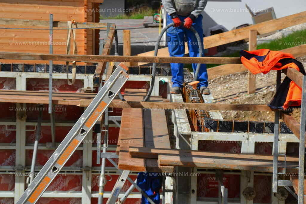 Betonverdichtung Betonwände | Arbeiter mit Betonrüttler stehend auf Wandschalung beim Verdichten des Wandbetons