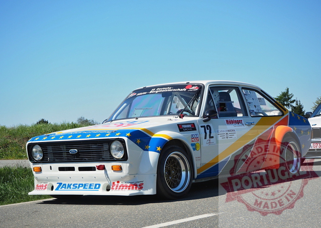 Ford Escort Zakspeed racing car parked on road | White Zakspeed Ford Escort race car with colorful livery under clear sky - Realisiert mit Pictrs.com