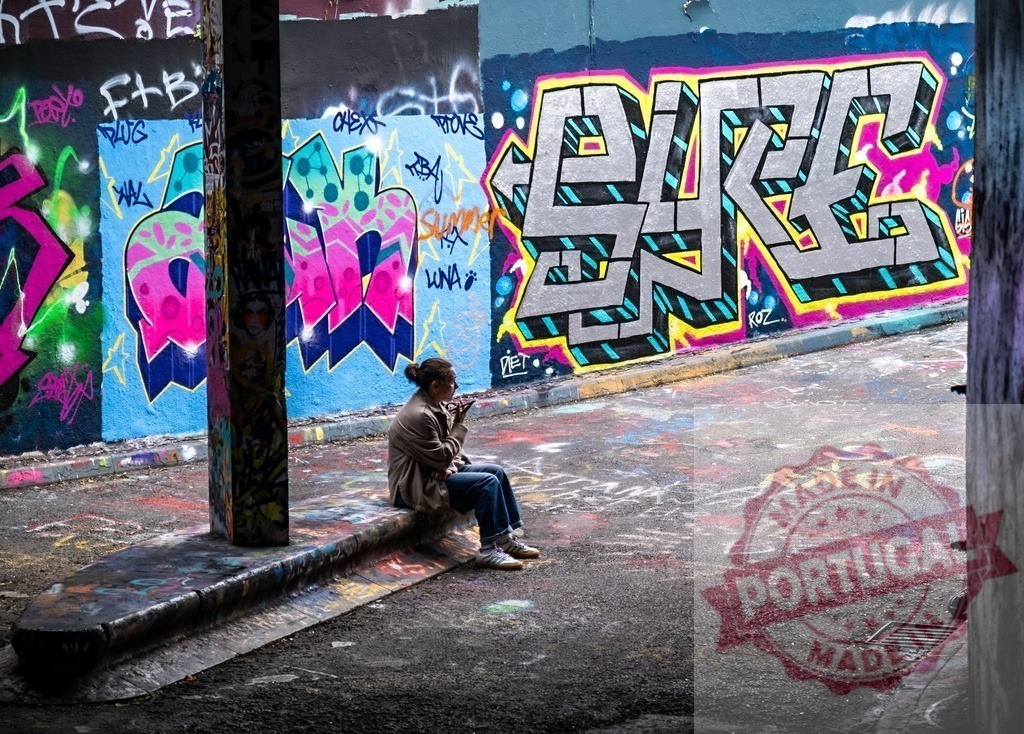 Person sitting in alleyway with colorful graffiti art | Person sitting on a ledge surrounded by vibrant street art and urban graffiti - Realisiert mit Pictrs.com