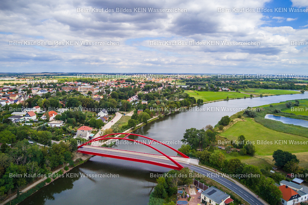 Calbe Saale-0014 | Die Luftaufnahme zeigt die Brücke über die Saale bei Calbe (Saale) im Salzlandkreis. Das Bauwerk quert den Fluss und verbindet die beiderseits der Saale gelegenen Bereiche der Stadt und ihrer Umgebung. Aus der Vogelperspektive werden die Brücke, der Flusslauf und die angrenzende Landschaft besonders deutlich. Die Aufnahme ist Teil des Mitteldeutschen Bildarchivs von Luftbildfotograf Steffen Lehmann. - Realisiert mit Pictrs.com