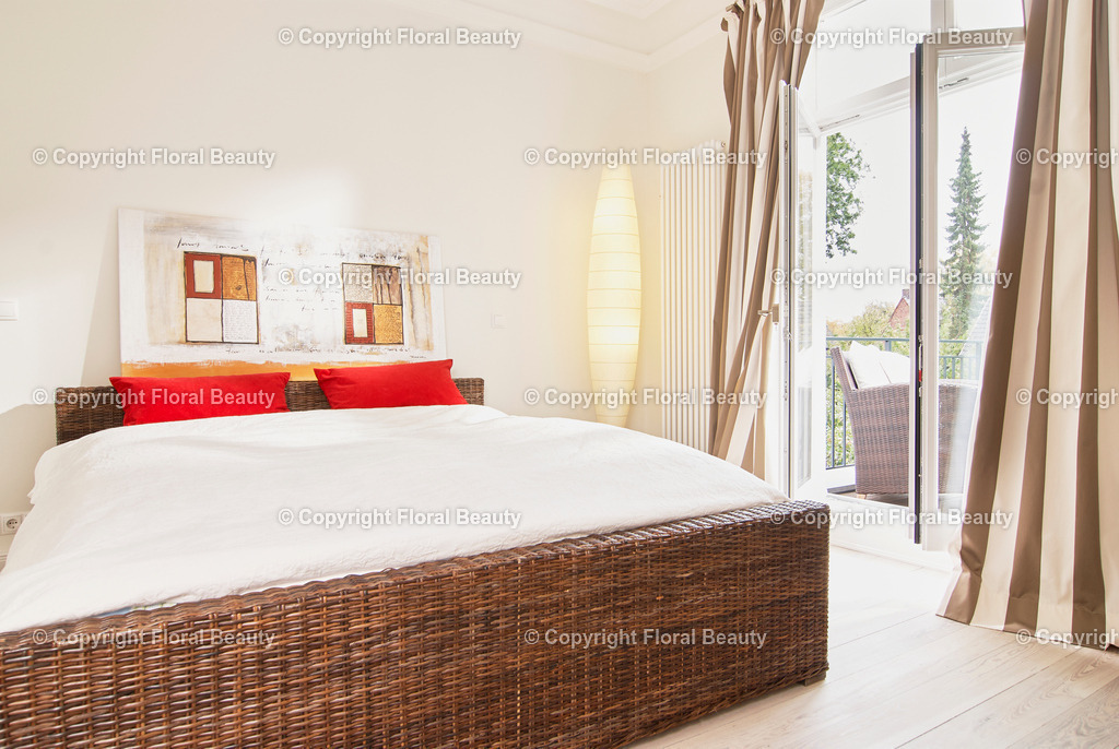 Schlafzimmer mit Korbbett | Schlafzimmer mit braunem Korbbett und roten Kissen. Offene Balkontür. - Realisiert mit Pictrs.com