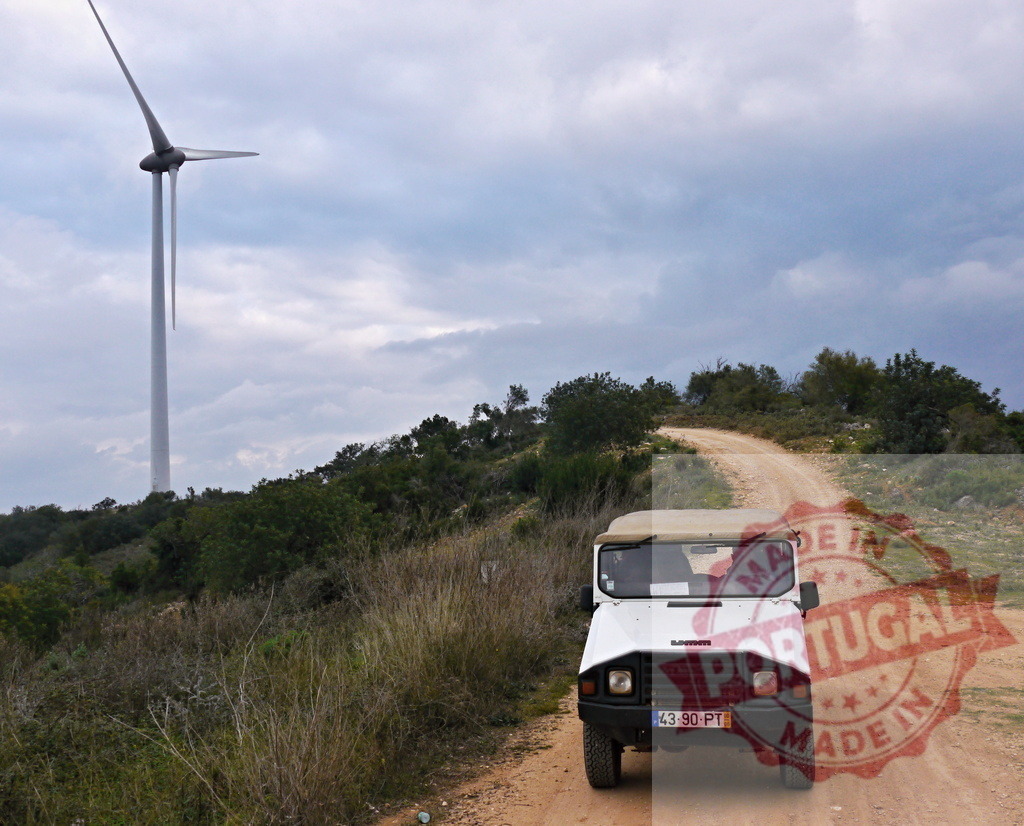 Off-road vehicle driving on dirt track near wind turbine | Off-road vehicle driving on a winding dirt road, approaching a large wind turbine - Realized with Pictrs.com